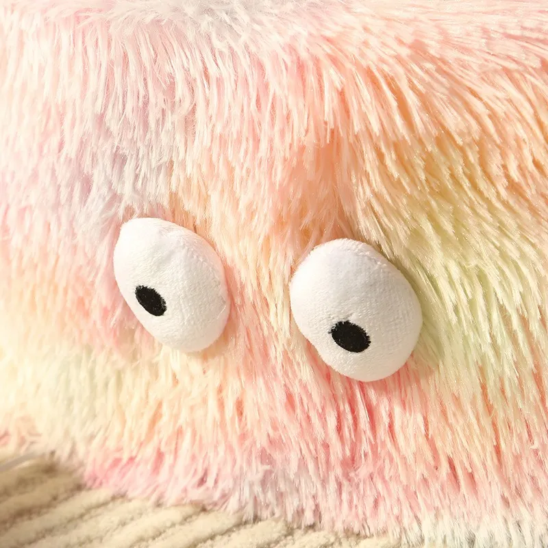 Close-up of a plush toy with large white eyes and pink fur.