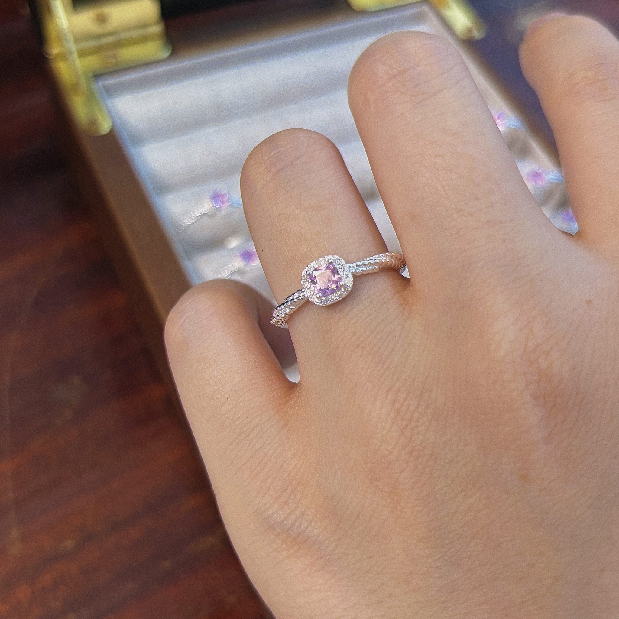 Pink cushion cut CZ halo ring on hand close-up with twisted band detail