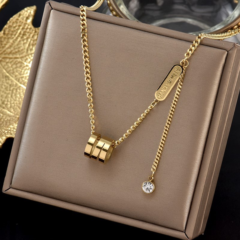 Gold tone necklace with a pendant on a beige jewelry box