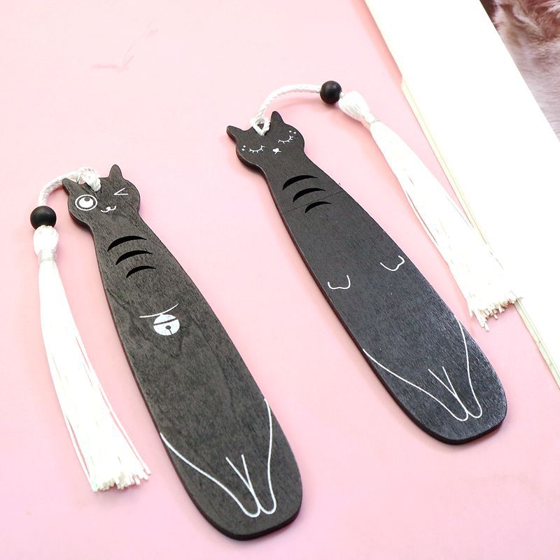 Wooden cat bookmark in use with open book and cozy reading setup