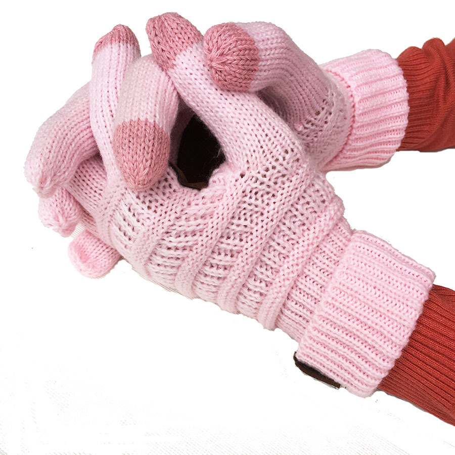 Close-up of hands wearing pink, European and American wool knitted touch screen gloves with a striped design, ideal as winter accessories. Thumbs exposed, the person dons a red long-sleeve shirt beneath. Hands are clasped together against a white background.