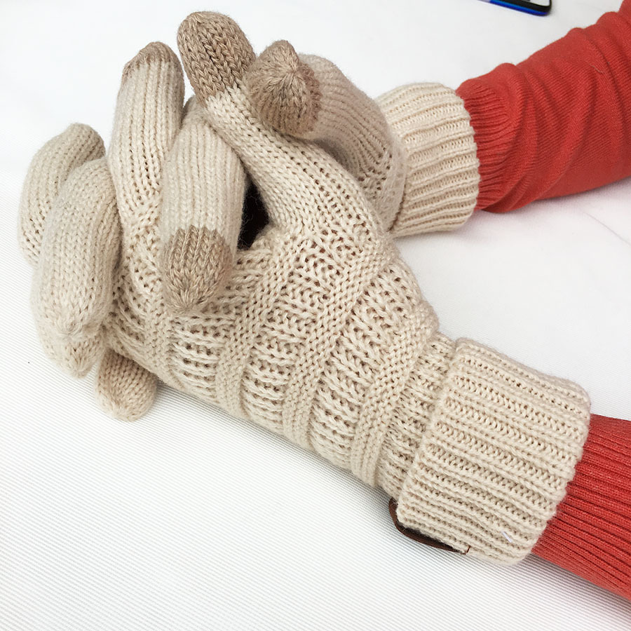 Two hands wearing the European and American Wool Knitted Turn-over Labeling Touch Screen Gloves in beige rest on a white surface. These gloves, crafted from soft acrylic fiber, feature a ribbed pattern with darker tips on the thumb, index, and middle fingers. Ideal for winter days, the wearer is dressed in a cozy red long-sleeve top.