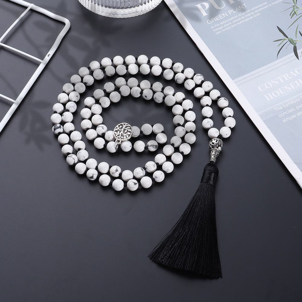 White beaded necklace with tassel on a dark background