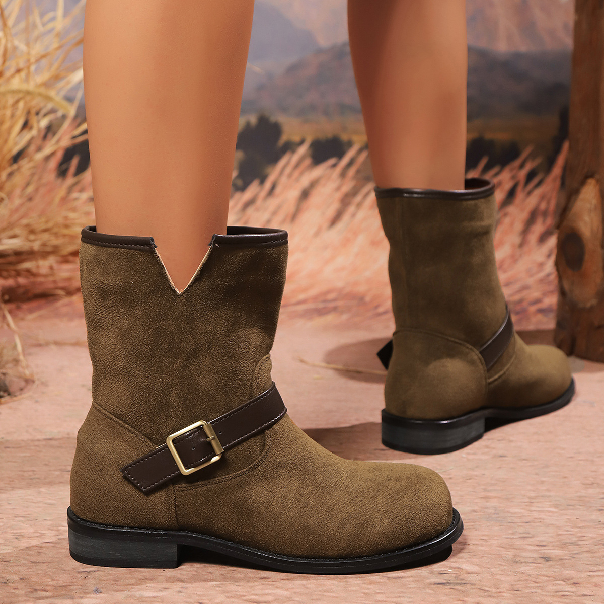 Dark brown suede-look boots showing the notched top, contrast buckle strap, stitched panels and low heel