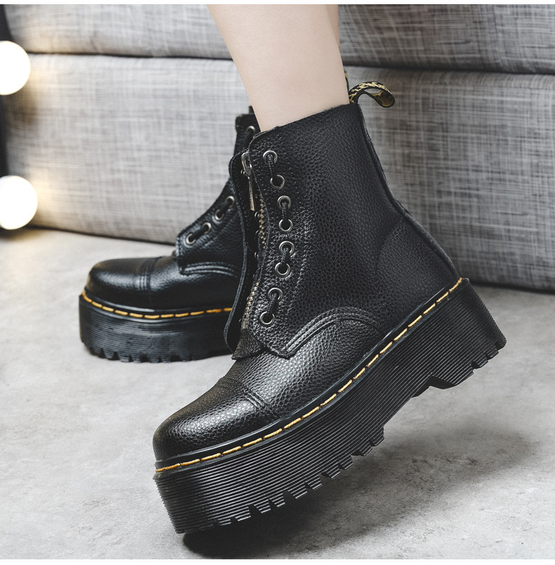 Close-up of black textured platform ankle boots with front zip, metal eyelets, yellow stitching and chunky soles