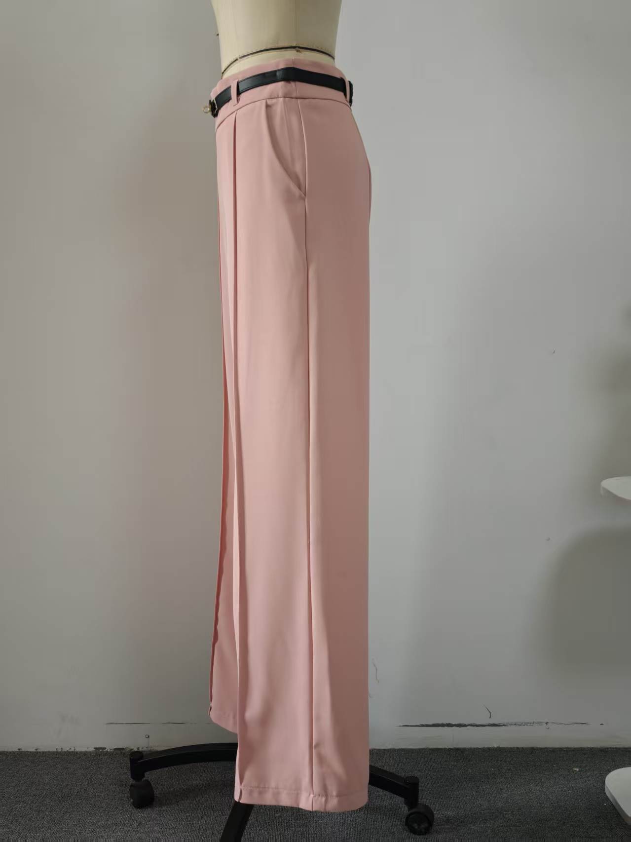 Actual pink trousers on a mannequin showing the waistband, belt loops, front pleat, side pocket and wide leg; belt inclusion is unconfirmed