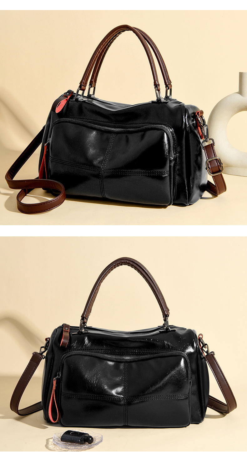 Black glossy crossbody bag showing the stitched front zip pocket, twin handles and detachable brown strap
