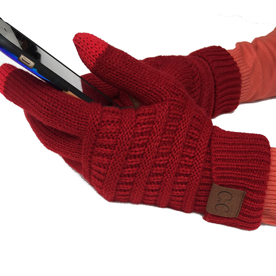 A person wearing European and American wool knitted turn-over labeling touch screen gloves is using a smartphone. These winter accessories are designed with a ribbed pattern and feature a small brown tag.