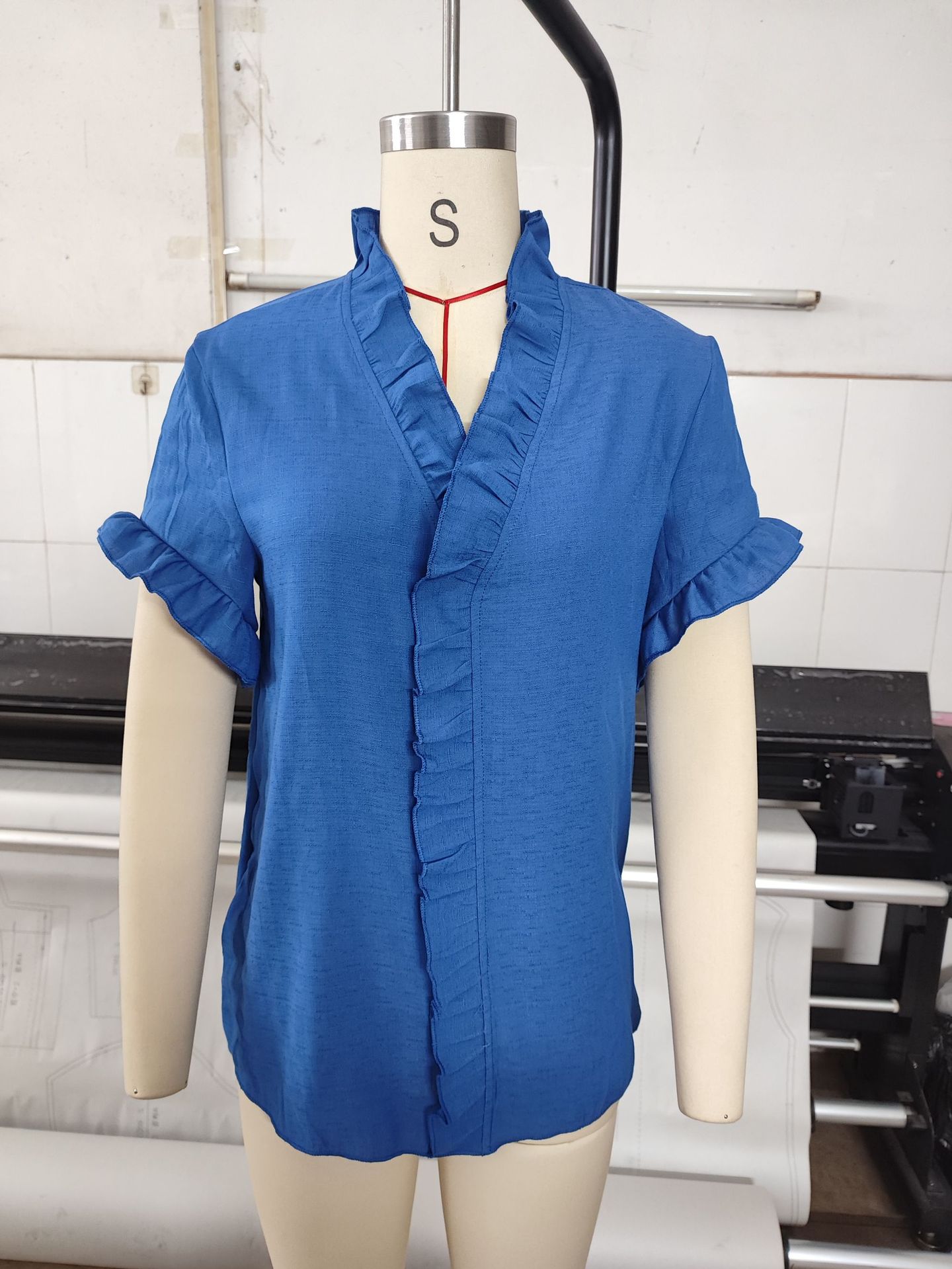 V-neck solid color top in light blue, close-up of ruffle trim and fabric texture