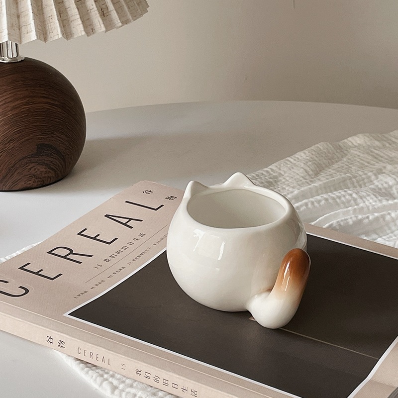 قط صغير سيامي كرتوني لطيف على فنجان قهوة رائع